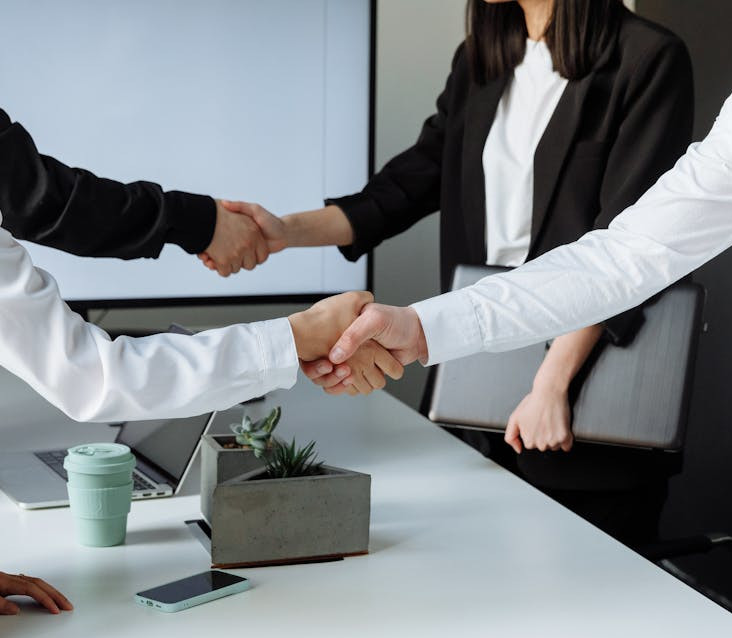 4 osoby elegancko ubrane, które się witają. Zbliżenie na ręce 